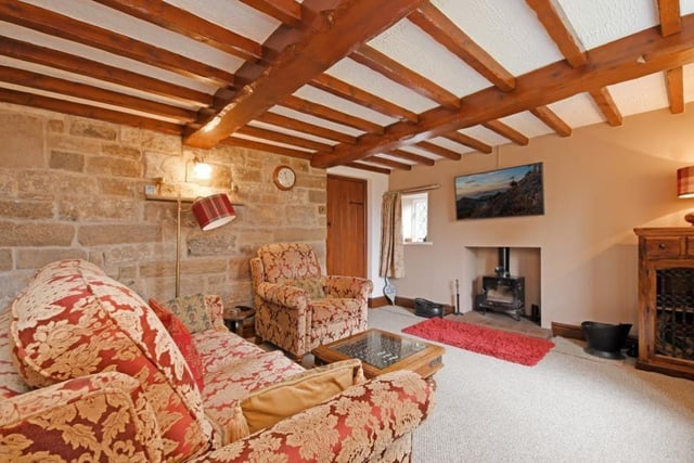 Exposed ceiling beams and a log-burning stove sitting on a tiled hearth catch the eye in this charming room.