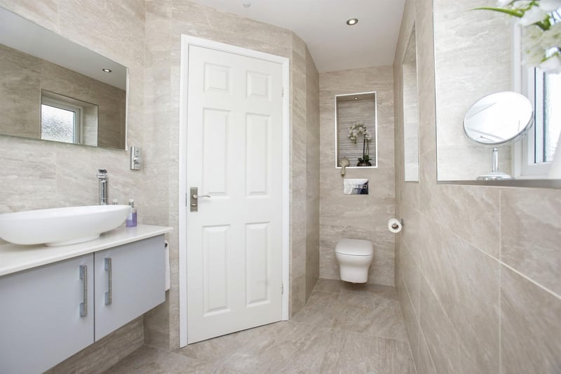 The shower room is fitted with a low flush WC with concealed cistern, a vanity unit with a floating wash hand basin and shower cubicle with rainfall shower and inset shelves with LED lighting.