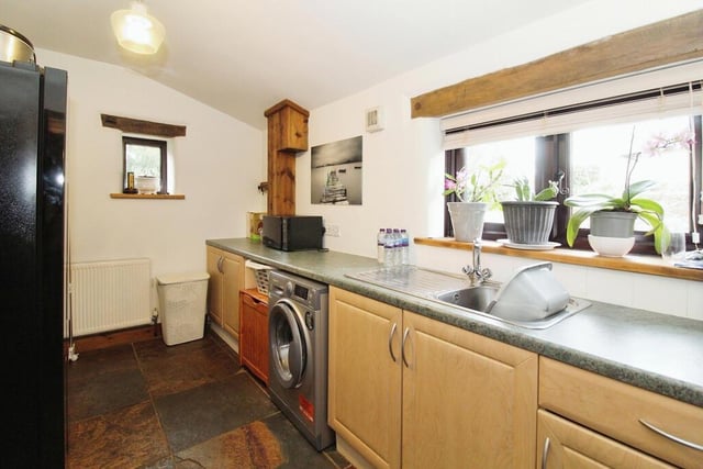 Close to the breakfast kitchen is this useful utility room, with space for a washing machine. It includes a fitted worktop with base units beneath, a stainless steel sink unit and a slate floor.