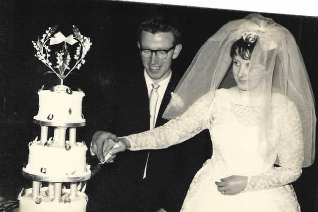 The couple cutting their double-tiered wedding cake in 1962