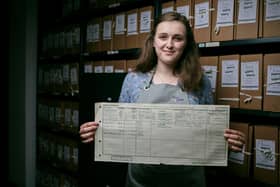 Emily Briffett, a Findmypast conservation technician,  holds the 1921 Census return for Thomas Moore, better known as Sir Captain Tom, who famously walked 100 laps of his garden during the pandemic and raised £33m for NHS charities. At the time the Census was taken Tom was 1 years old and living in Keighley (photo: Mikael Buck/Find My Past/The National Archives)