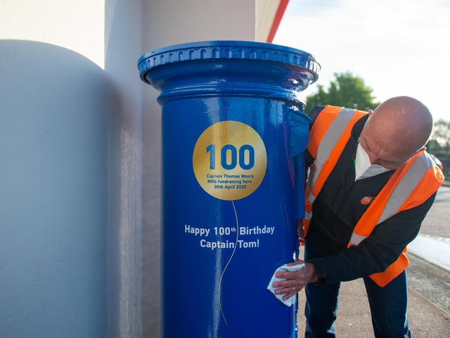 A man polishes a letter box painted blue to mark the 100th birthday of Second World War veteran Captain Tom Moore close to the home in Marston Moretaine, near Bedford.