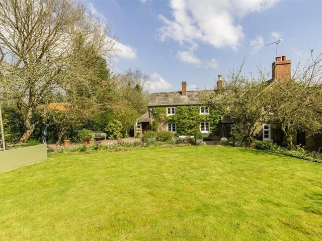 The front garden is laid to lawn and has mature planted borders, trees and raised vegetable and fruit beds.