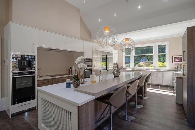 The contemporary kitchen has an island breakfast bar and integrated appliances including an induction hob, fridge freezer with wine cooler, microwave oven and coffee machine.