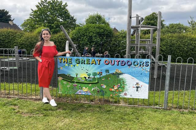 Artist Lily Hammond pictured with the new mural she created with help of local schoolchildren at Ashover playing fields