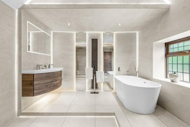 The bespoke main bathroom in which the shape of the hand basin vanity unit complement the bath.
