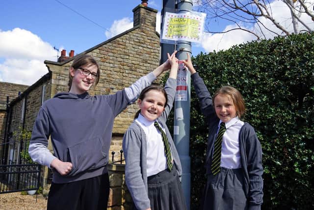 Year 6 pupils Darci, Darcy and Lillie next to a poster created by pupils during a road safety project at Walton Holymoorside Primary School.