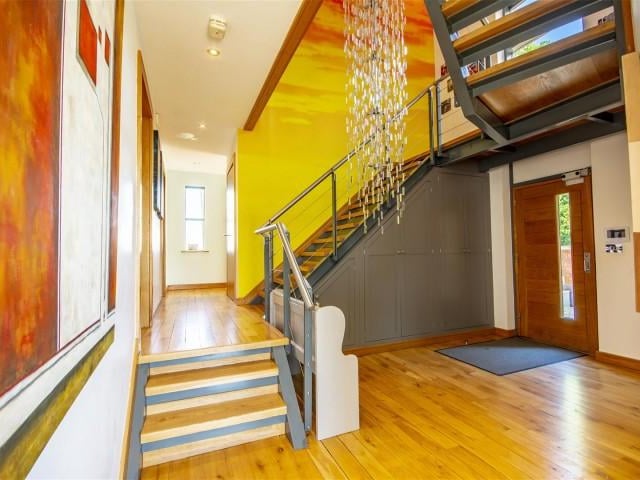 The entrance hall has wood flooring with underfloor heating, a wall mounted security alarm panel and fitted under stair cupboards.