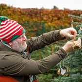 Craig Best, general manager for Peak District National Trust, hangs a handcrafted wooden decoration to an outdoor tree (photo: Kev Dunnington)