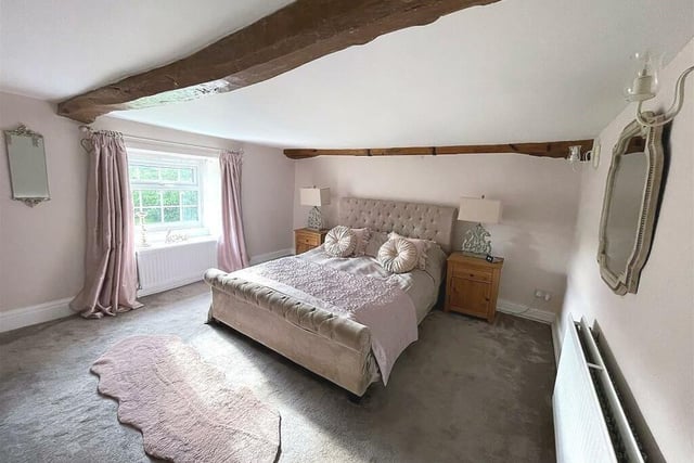One of two bedrooms on the first floor has exposed ceiling beams; the other has a feature stone wall.