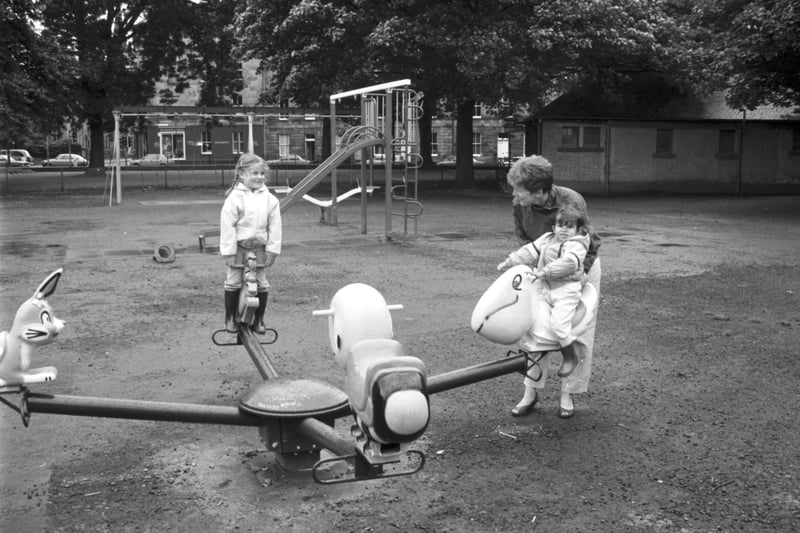 Mum and children playing on the roundabout at the new playground in the East Meadows, Edinburgh, August 1985.