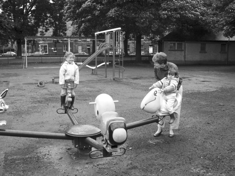 Mum and children playing on the roundabout at the new playground in the East Meadows, Edinburgh, August 1985.
