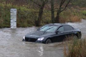 The car was stranded in the flood water along the road.