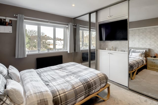 Built-in mirrored wardrobes and a large rear-facing window are eye-catching features of this room.