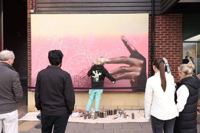 Peachzz works on her second mural, as shoppers look on.