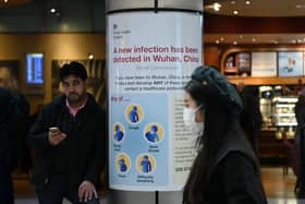 A woman wearing a face mask passes a Public Health England sign, warning arriving passengers that a virus, Coronavirus, has been detected in Wuhan in China, at Terminal 4 of London Heathrow Airport in west London on January 28, 2020. - Chinese President Xi Jinping said Tuesday the country was waging a serious fight against the "demon" coronavirus outbreak and pledged transparency in the government's efforts to contain the disease. (Photo by DANIEL LEAL-OLIVAS/AFP via Getty Images)