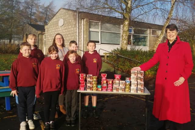 Headteacher Sarah Owens and pupils from Bakewell Methodist Junior school hand over the Christmas puddings they collected.