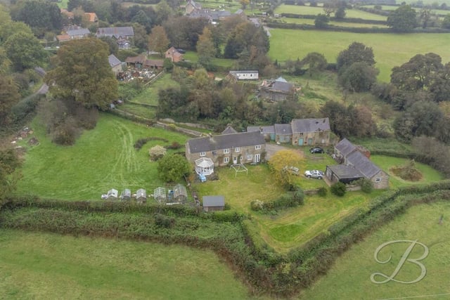 Drone footage shows the farmhouse surrounded by greenery.