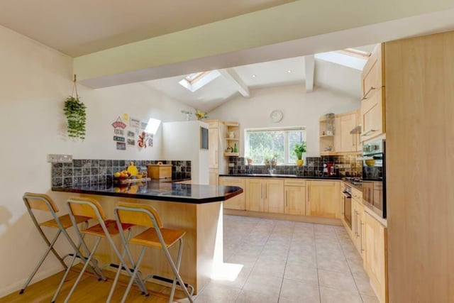 The kitchen area has a vaulted ceilting with roof windows. Fitted base and wall units incorporate matching work surfaces, tiled splashbacks and under counter lighting. The work surface also extends to provide breakfast seating for three chairs. Appliances include the four-ring gas hob with an extractor hood above, two fan assisted ovens, a dishwasher and an integrated full-height fridge/freezer.