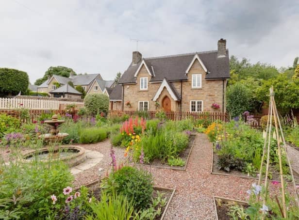 This beautifully designed front garden has gravelled paths running between flower beds containing mature shrubs that surround a central water feature.