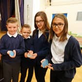 Spire Junior School pupils are partnering with Chatsworth Burning Man artist Dana Albany to create a sculpture. Pictured, Dana and pupils are holding recycled glass like that which will be used for 'Coralee'