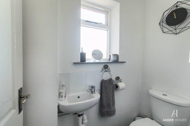 Close to the entrance hall is this downstairs toilet, featuring a low-level WC and wall-mounted hand basin. There is also vinyl flooring, splashback tiling, a radiator and a double-glazed window to the side of the house.