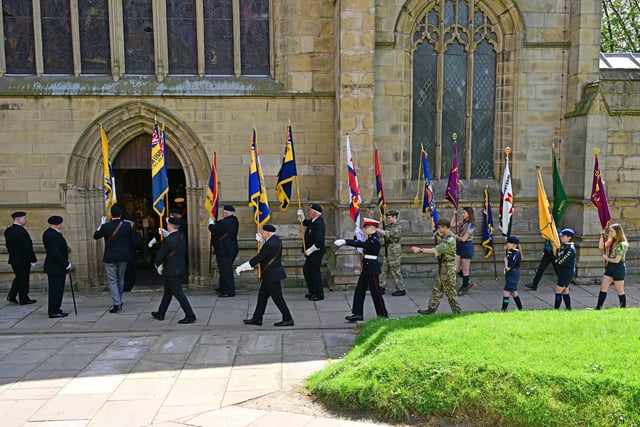 Flag bearers for the Royal British Legion enter St Mary and All Saints church for the service
