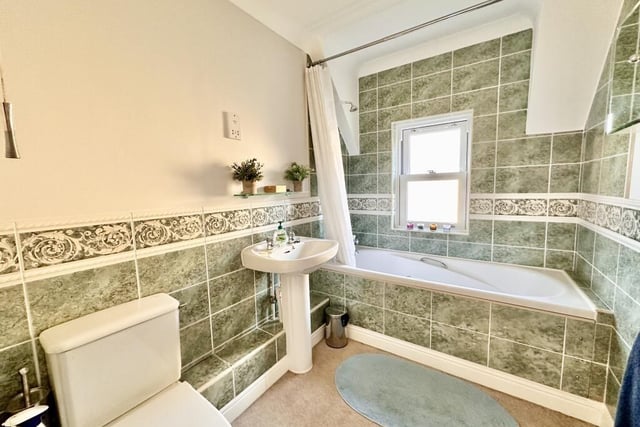 The family bathroom is half tiled with decorative border tile and contains has a full suite in white.