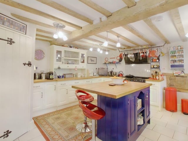 Fitted storage cupboards are complemented with solid oak worktops incorporating a Belfast sink. A matching island unit offers a breakfast bar, work surface, cupboards and shelving. There is a gas range cooker with extractor hood over. Integrated appliances include a dishwasher, fridge and wine rack.