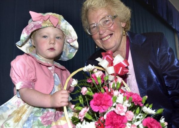 Melissa Oliver aged two giving a basket of flowers to Deputy Mayor Beryl Roberts. Wilby Carr Community Centre Summer Fayre 2000.