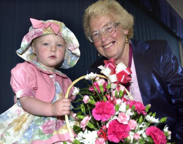 Melissa Oliver aged two giving a basket of flowers to Deputy Mayor Beryl Roberts. Wilby Carr Community Centre Summer Fayre 2000.