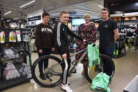 Hayden Hudson sat on his new bike with (l to r) Tracey Hudson, Victoria Walton (Frasers Group) and David Fletcher (Evans Cycles Store Manager) stood behind.