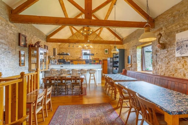 Exposed stonework and ceiling beams give character to the open plan kitchen/dining area that includes a breakfast bar.

​