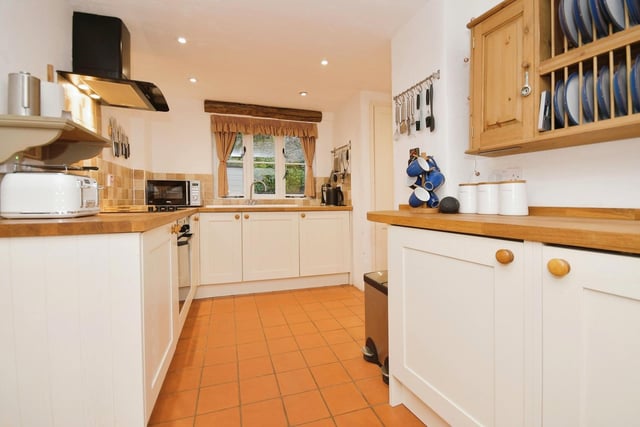 The kitchen has wall and base storage units with hardwood worktops and integrated appliances including hob, oven and extractor over, dishwasher, two fridges, freezer and washer dryer. There is an enamel sink and tiled splashbacks. The room looks out over the garden.