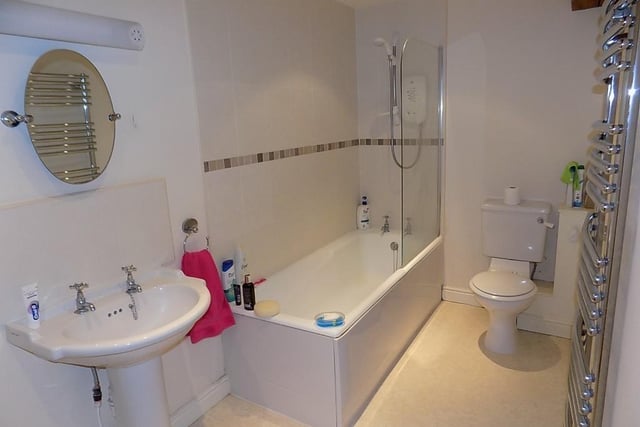 Part of the principal bedroom suite, the bathroom has a white bath with fitted electric shower, wash basin and wc.  There is a built-in linen/airing cupboard.