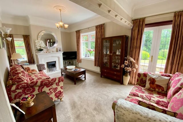 A larger than average reception room contains a marble fireplace with coal-effect gas fire. Doors open out onto the side patio and seating area.