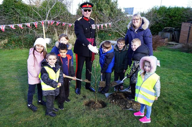 Her Majestys Vice Lord Lieutenant Col. John Wilson OBE and Spire Infant and Nursery School headteacher Kelly Hill plant the Queens Green Canopy tree with help from some children.