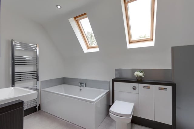 The en suite to the master bedroom is a fabulous white suite, comprising a panelled bath, walk-in shower enclosure, vanity unit with wash hand basin, open shelving and cupboards, and also a low-level WC with fitted storage. Two Velux roof windows, recessed lighting and a chrome, heated towel-rail add to its appeal.