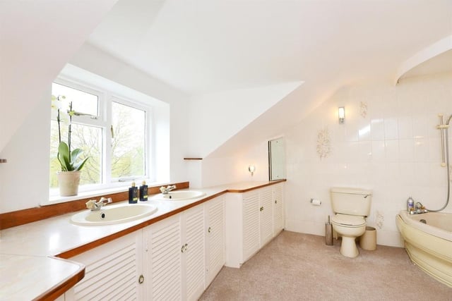 This luxurious and large ensuite has double sinks with storage below that runs the length of the room. The suite includes a corner bath with overhead shower and a wc.