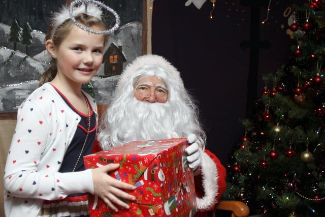 Grace Hyman, 8, from St Mary's Primary School, Chesterfield, with Santa in his grotto after he arrived on the school's roof  in 2011.