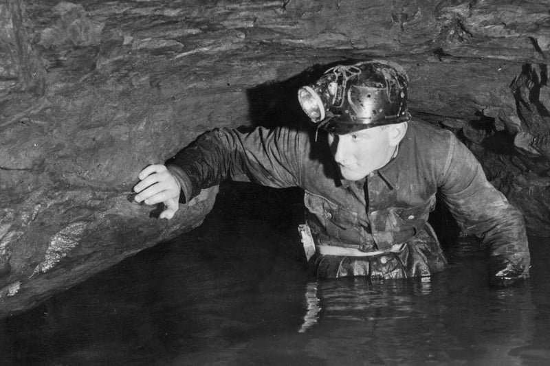 Caver John Buxton wades through limestone caves at Speedwell Water, Peak Cavern, in the Peak District around 1960.