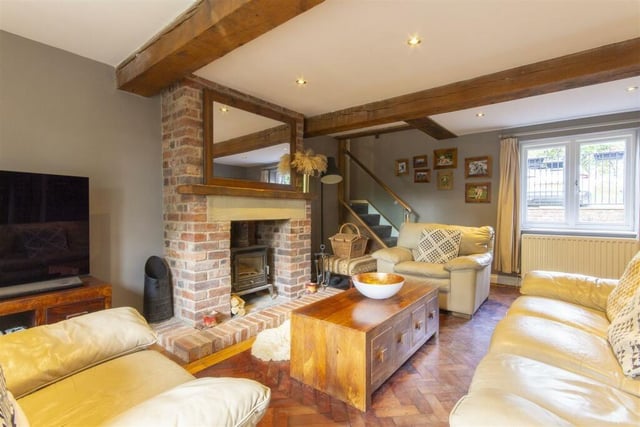 Exposed wooden beams, a brick fireplace that houses a multi-fuel stove with a stone lintel above, parquet flooring and French doors opening onto the rear patio are features of the cosy living room.