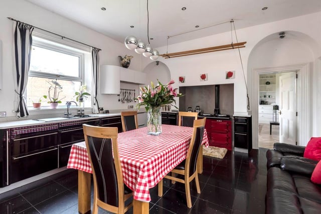 The large and spacious homely kitchen has a  red AGA cooker, modern wall and base units with granite countertops.