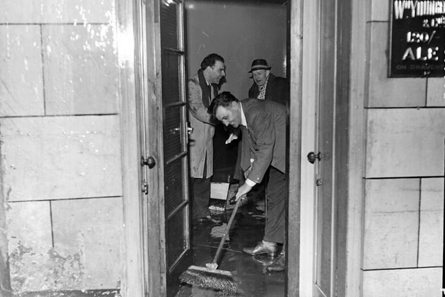 Staff sweep the water out the door of the Halfway House pub in Fleshmarket Close, just off Cockburn Street, after flooding in Edinburgh in January 1963.