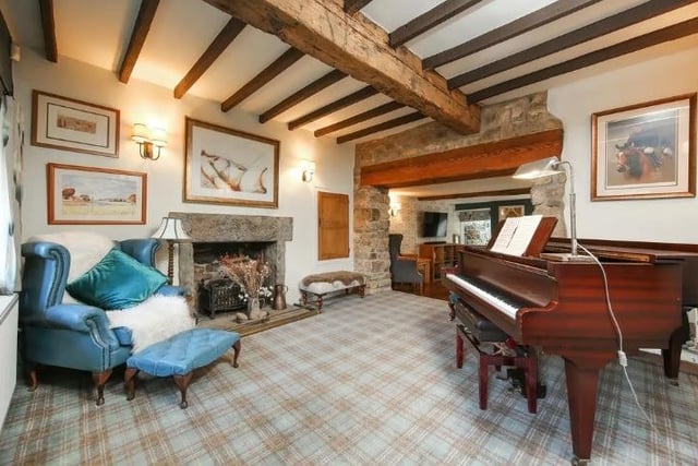 Impressive ceiling beams, exposed stone wall and an open fireplace are eye-catching features of the music room which adjoins the formal lounge.