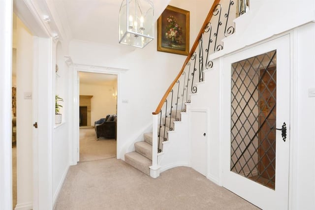 An ornate staircase leading up to the first-floor bedrooms and bathrooms is a focal point of the hallway where there are storage cupboards.