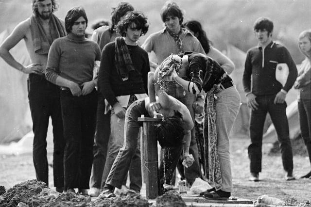 27th August 1970:  Hippies, students and music lovers at East Afton Farm, near Freshwater, during the Isle of Wight pop festival. Festival-goers camping at the five day long event organised by Fiery Creations, queue up to wash at a tap.  (Photo by Roger Jackson/Central Press/Getty Images)