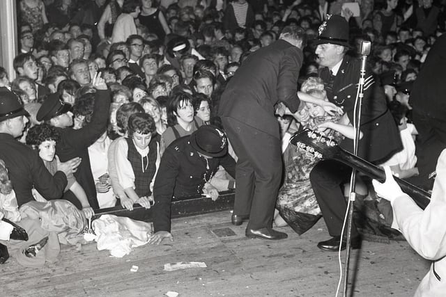 Buxton Advertiser Archive, John Lennon plays on as fainting fans are carried from the audience at Buxton's Pavilion Gardens in 1963