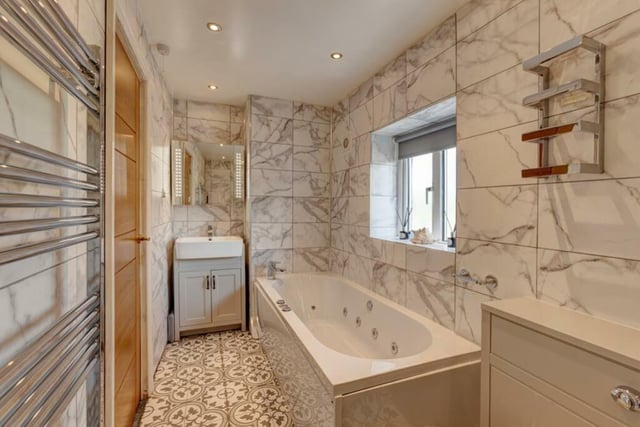 The family bathroom has a white suite comprising spa bath, walk-in shower cubicle with fitted shower,  hand basin with storage beneath and a wc.