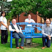 Andrew Woodard (left) sits on the bench he donated to Chesterfield Royal Hospital and celebrates with staff members.
